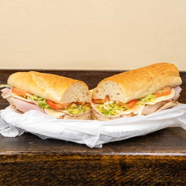 A large sub sandwich, cut in half, filled with meat, cheese, lettuce, and tomato.