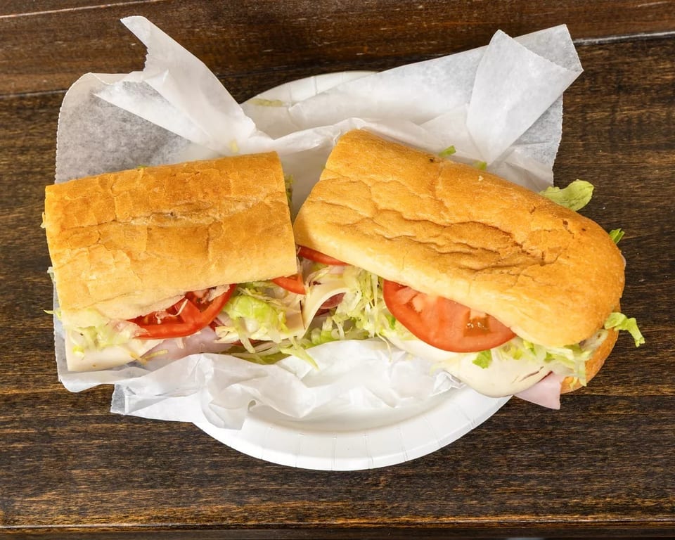 A large sub sandwich, cut in half, filled with meat, cheese, lettuce, and tomatoes.